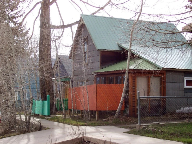 two houses with green trim and orange doors on one and a silver roof