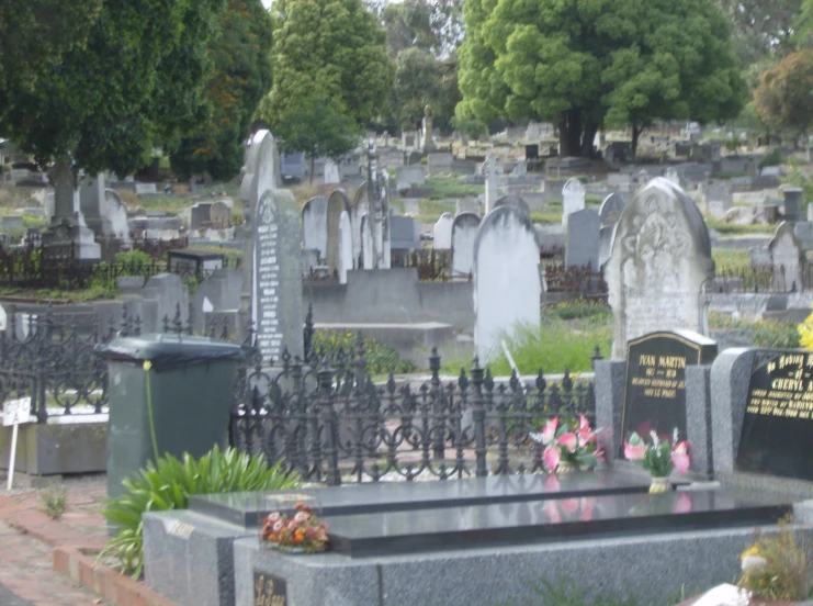 a cemetery full of graves with a fenced area next to it