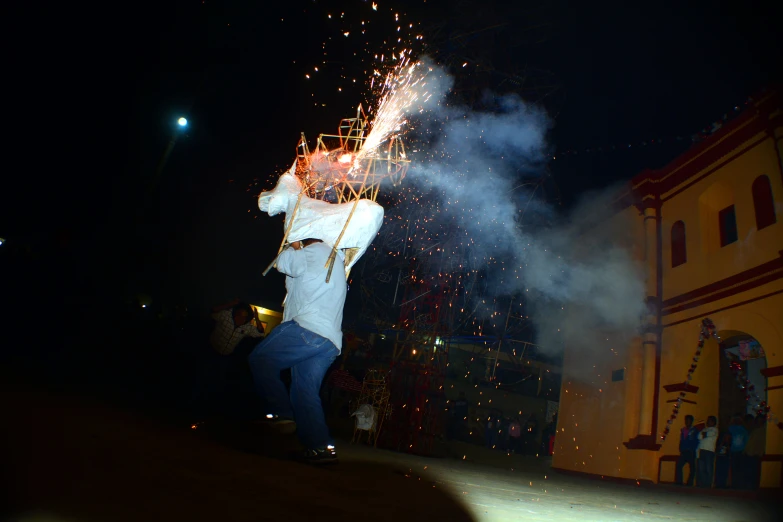 a man wearing white is holding a fireworks display