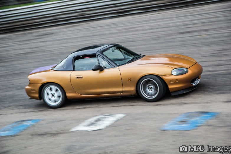 an orange sports car on the road with a white and black top