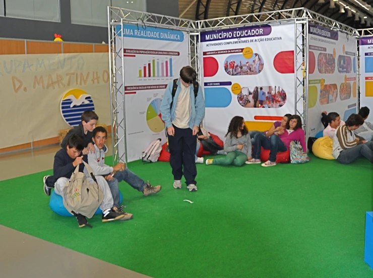 a group of people sit on bean bag seats in front of a poster board