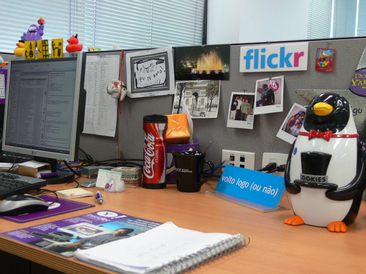 a stuffed penguin sitting at a desk in front of a computer