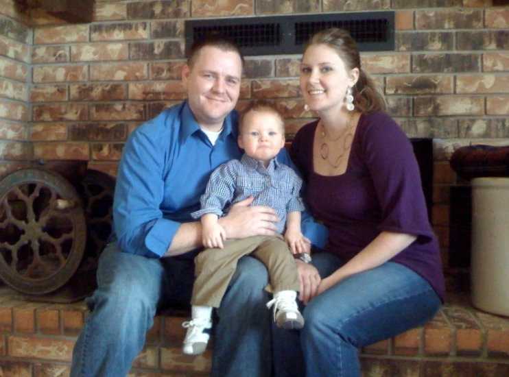 man and woman pose for the camera with their toddler boy