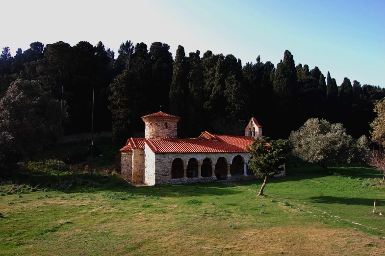 the exterior of a small brick church in the middle of trees