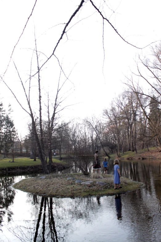 three people stand on an island in the middle of the pond