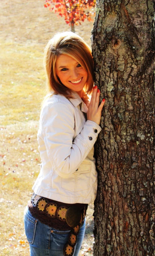 a young woman is leaning against a tree