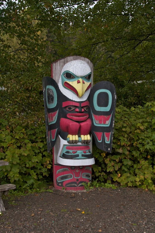 a carved bird sitting next to trees near a park bench