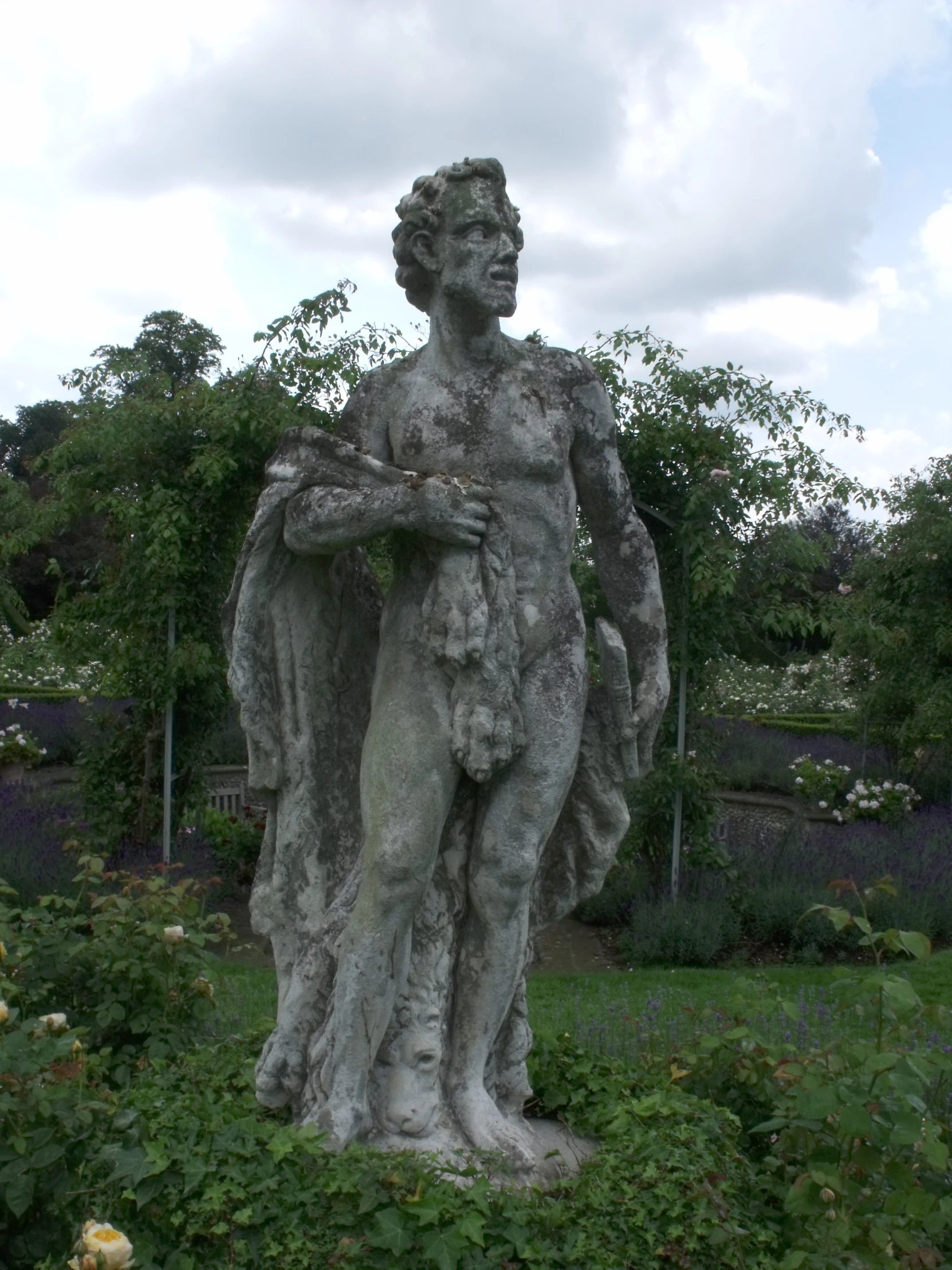 statue of man holding woman near bush and fence