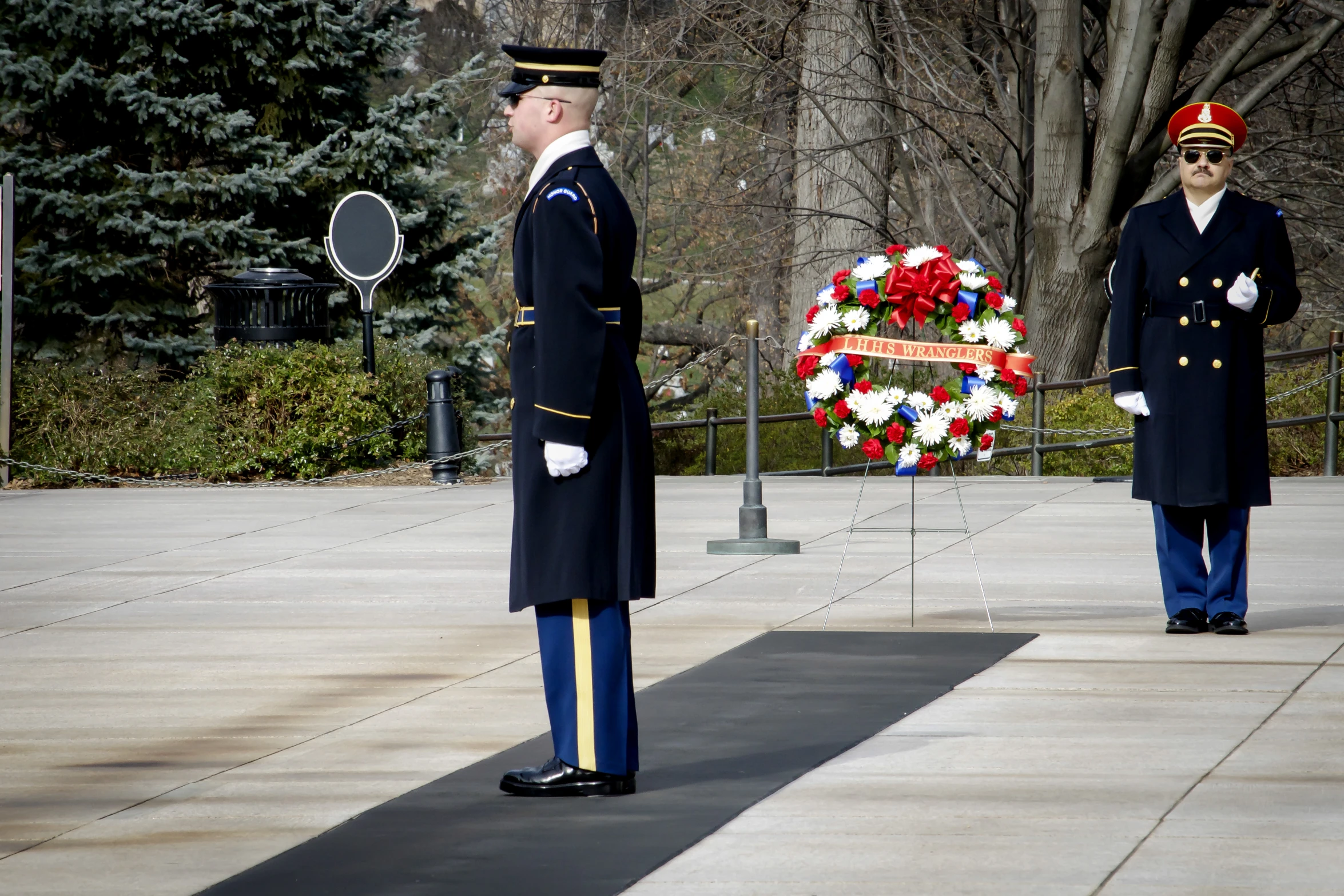 two men in uniform stand by wreaths at park