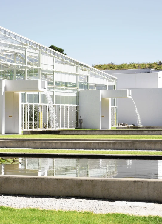 a green house with a water feature in front of it