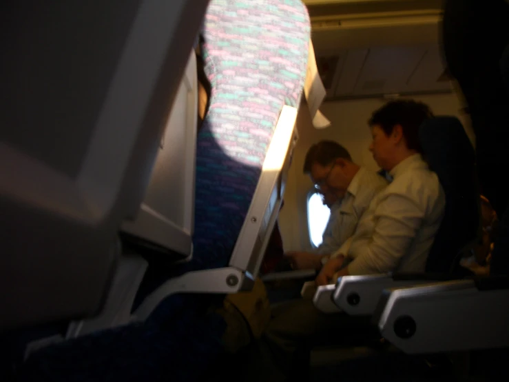 three men siting next to each other on a plane