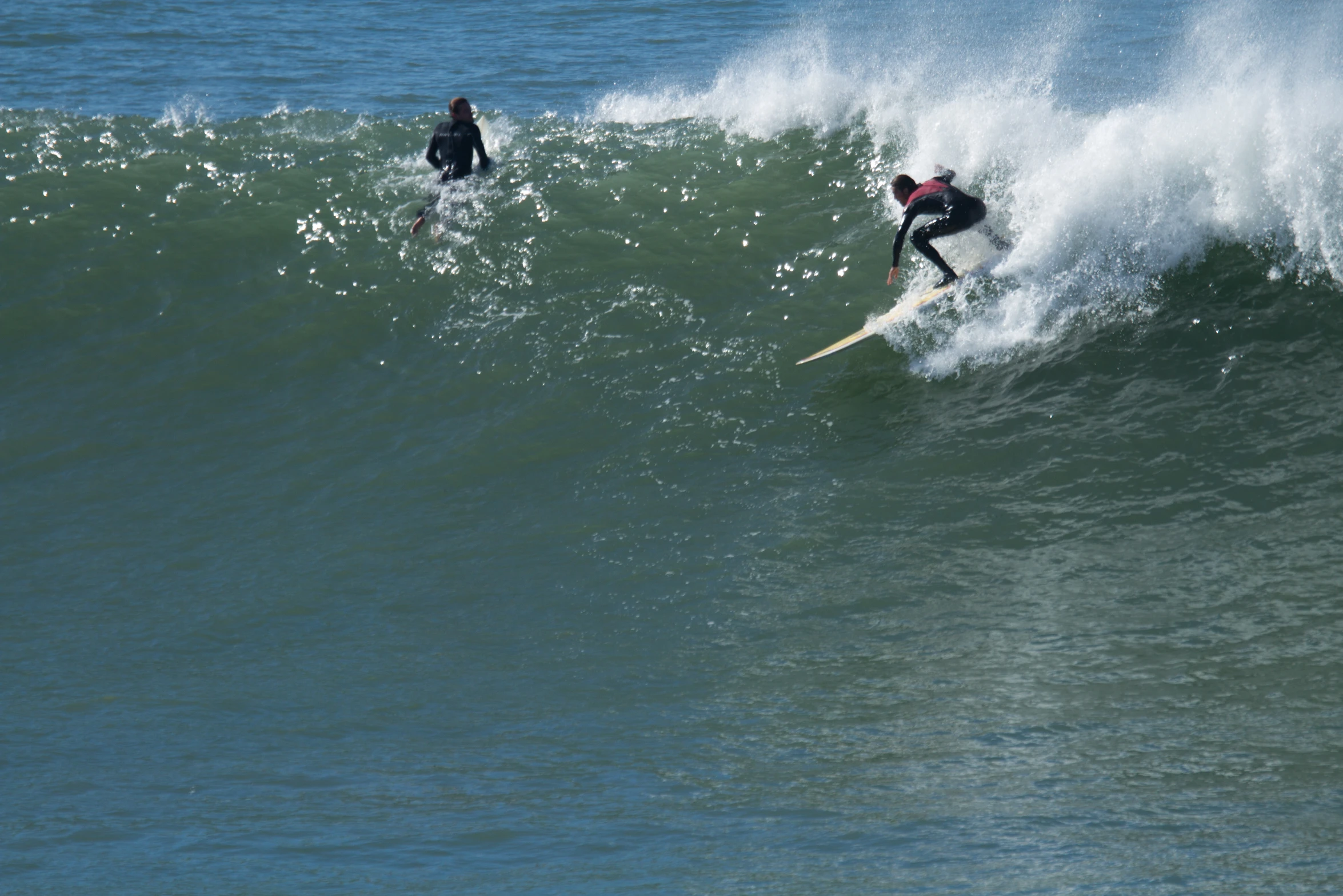 two surfers are surfing on the large waves