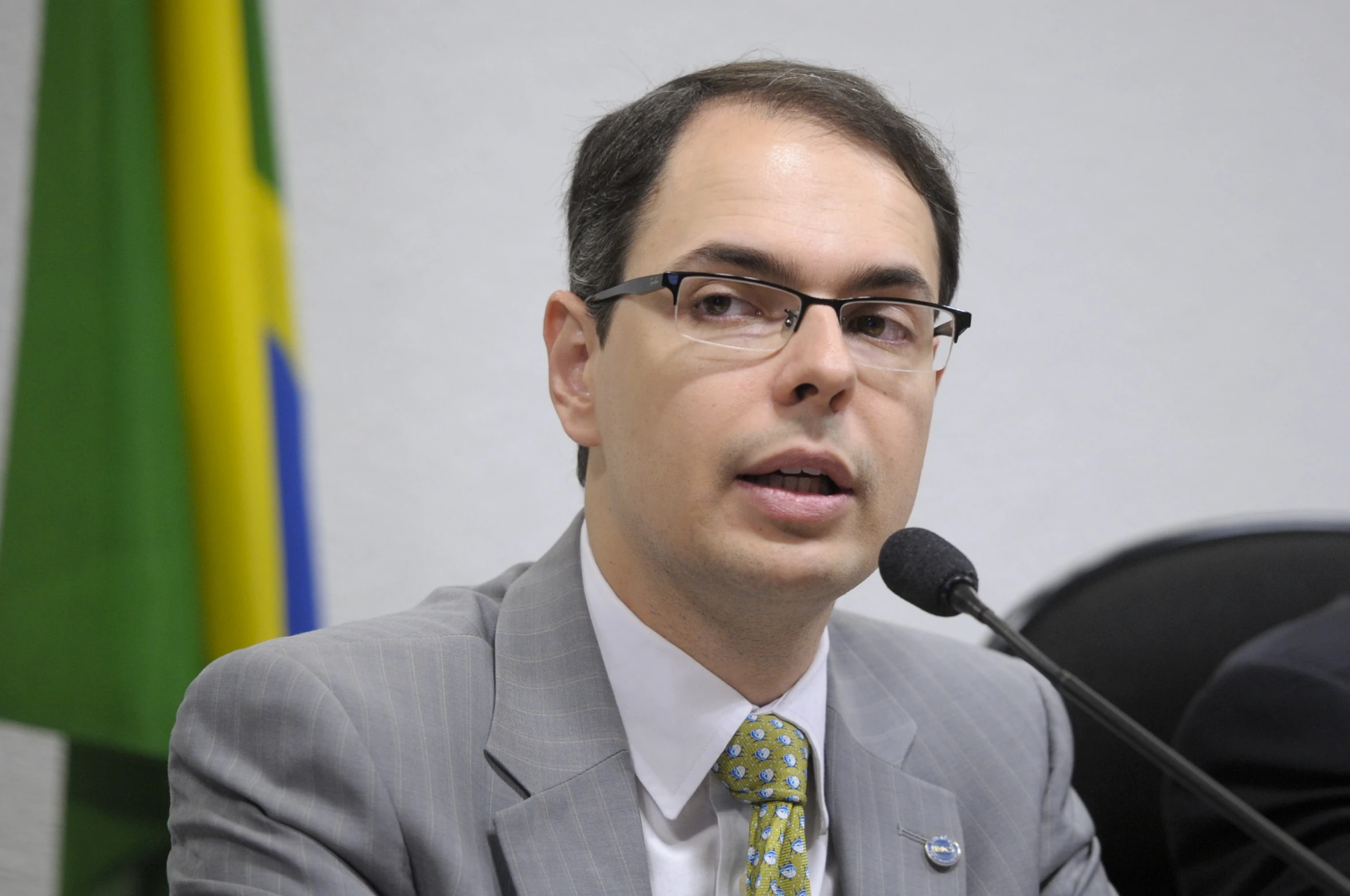 a man wearing glasses and a suit in front of a microphone