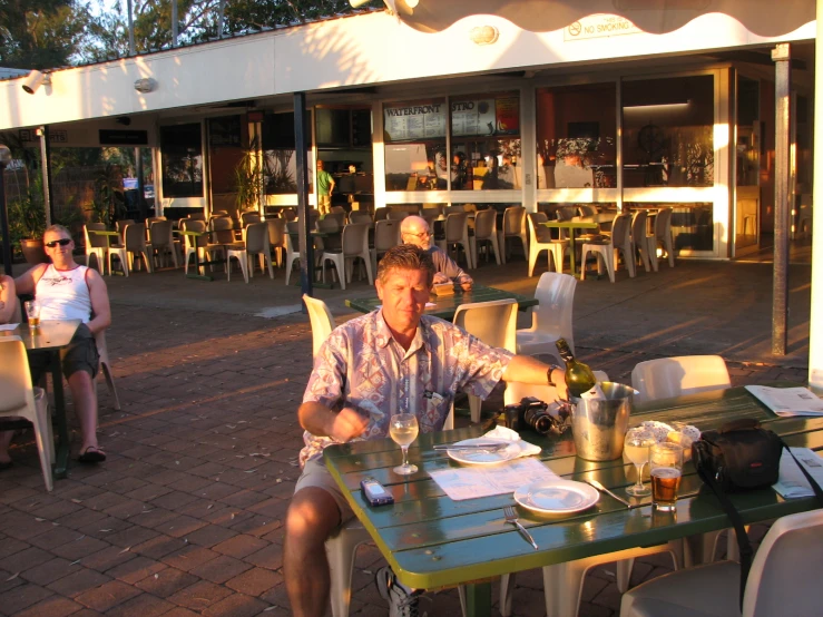 two men sitting at a green table with food