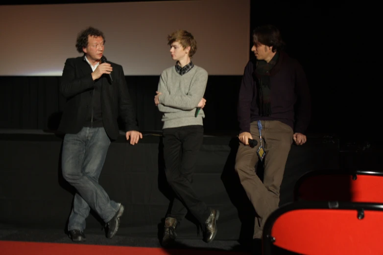 three men who are standing together in the dark