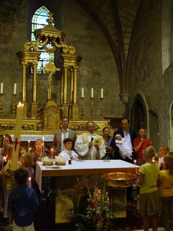 group of people celeting in church with priest reading from paper