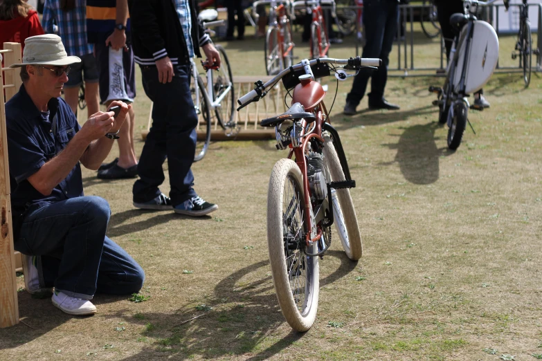 a man sits next to a bicycle and uses his phone