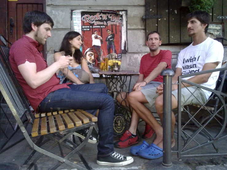 four people sitting at an outside table with drinks