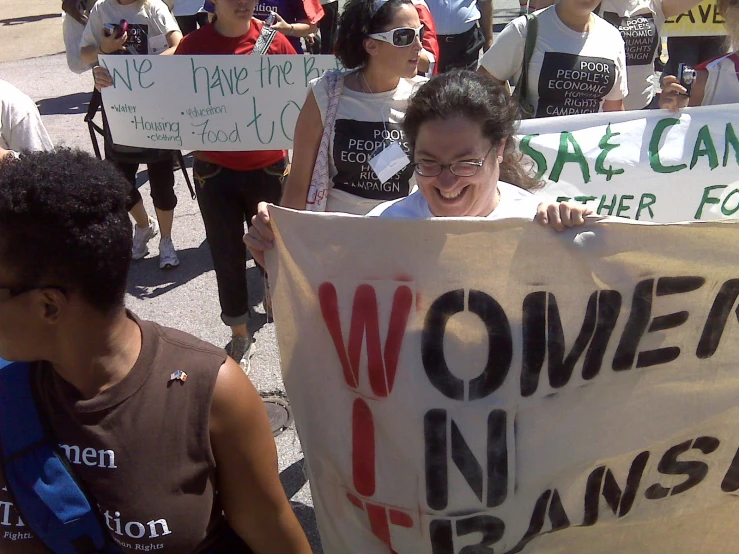 women in transit holding up signs while walking down the street