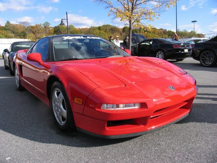 a red sports car parked next to other cars