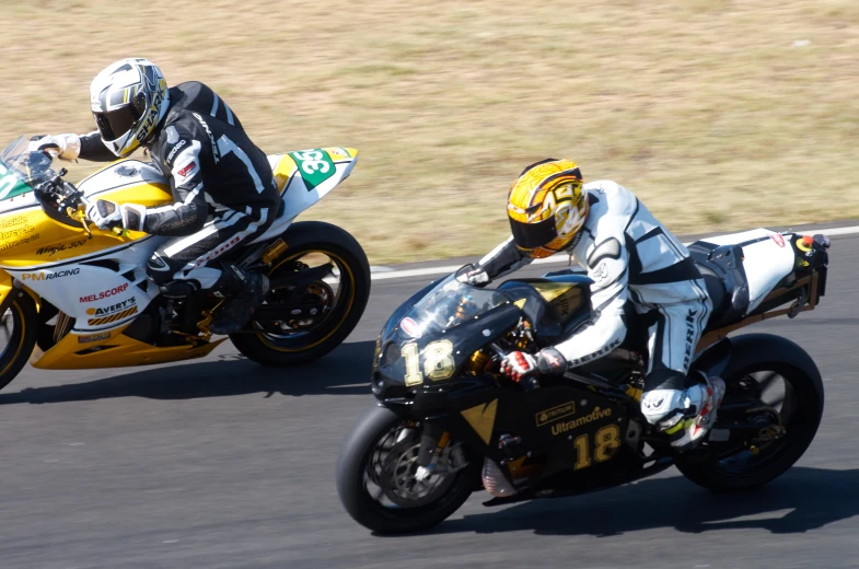 two people riding motorcycles on a road