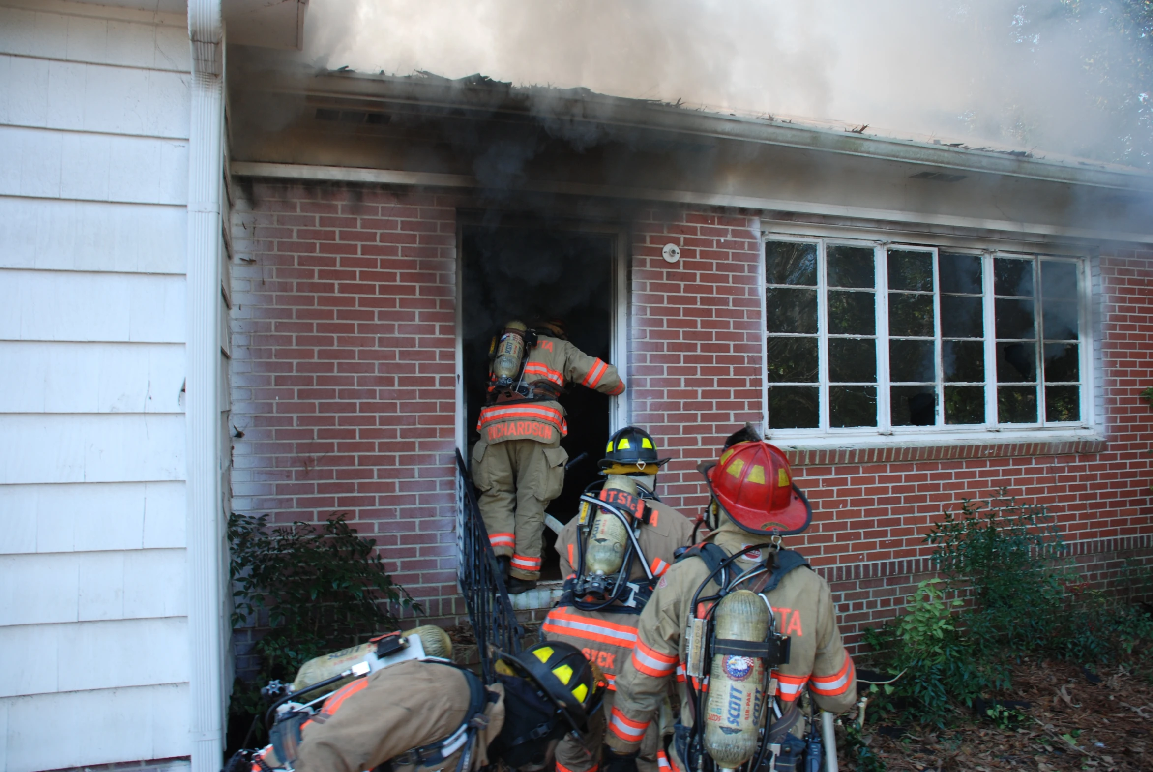 two firemen are putting out the door of a house