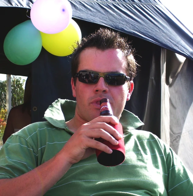 a man with a party hat on, holding a soda bottle