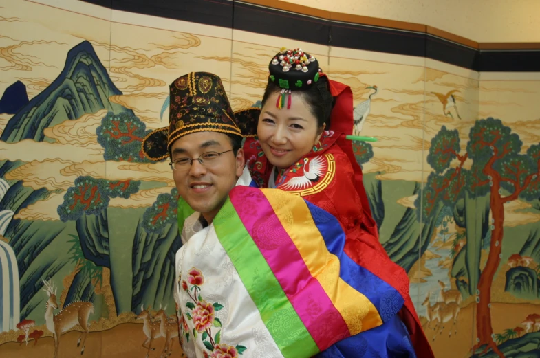 man and woman in costume holding rainbow flag next to a painted wall