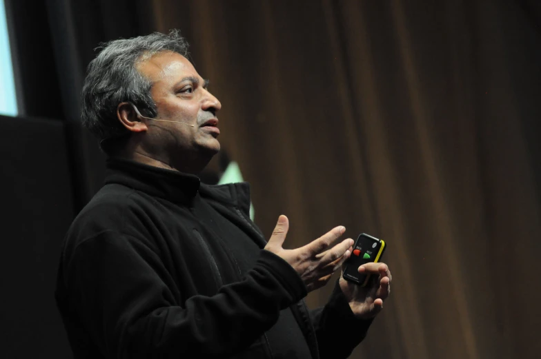 a man in a black jacket holding up a cell phone