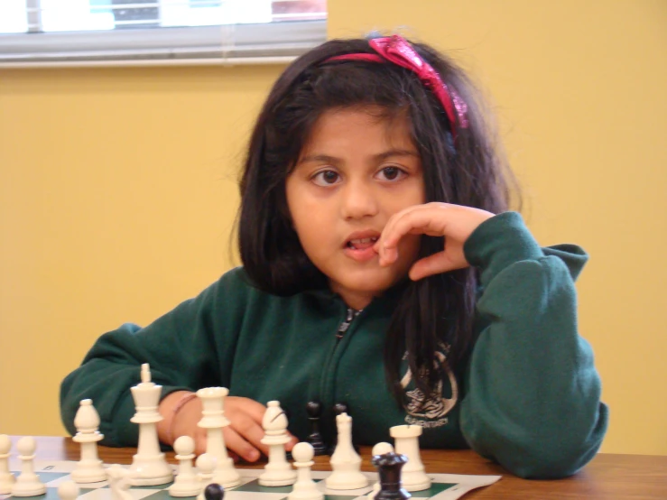 a small girl at a table playing chess