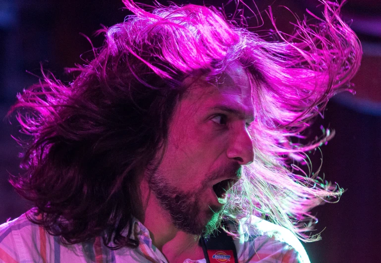 a young man with long hair on stage singing into a microphone