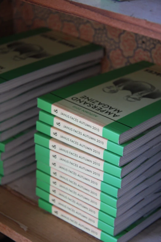 several stacks of green and white books on wooden shelves