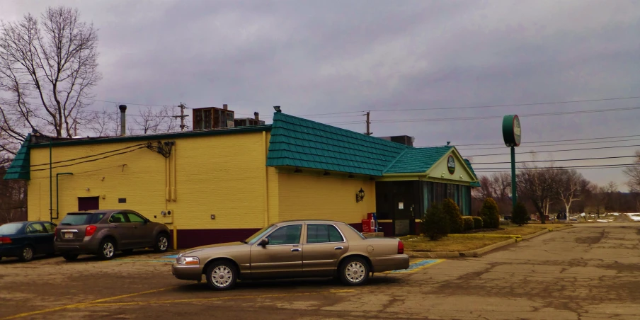 a car parked outside a yellow building with a metal roof