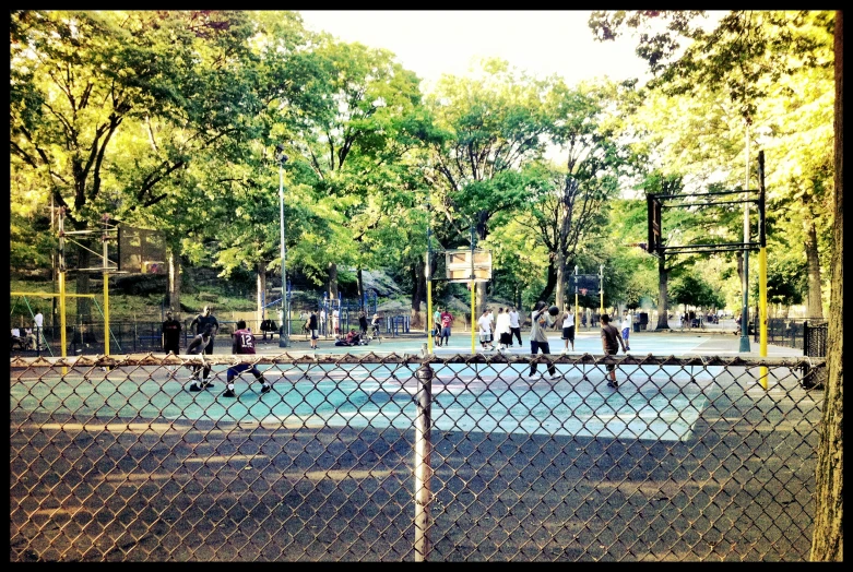 people in the distance playing basketball on a chain link fence