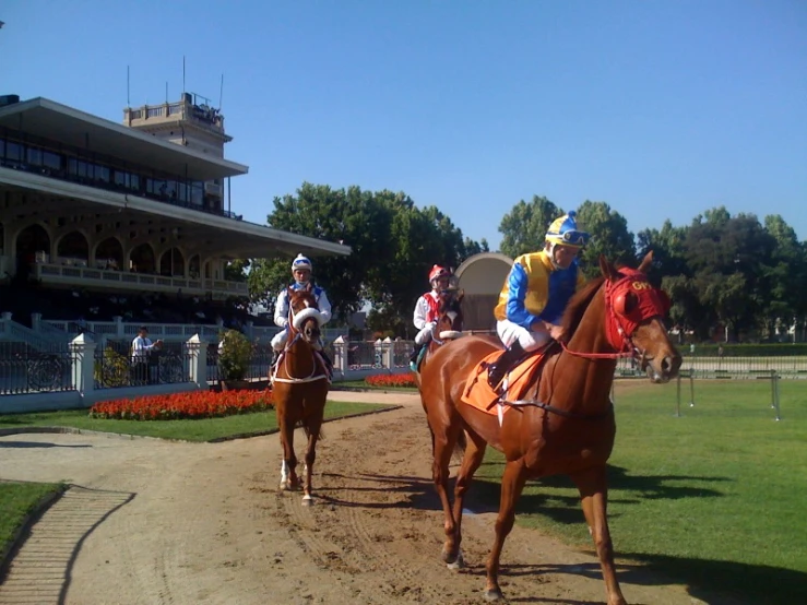 some jockeys on horses in front of a building