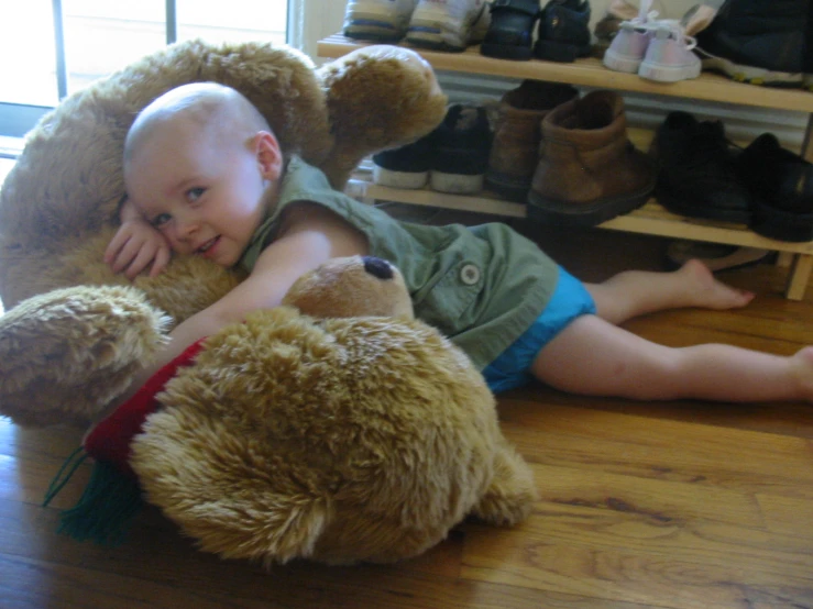 baby and teddy bear sitting on wooden floor in store