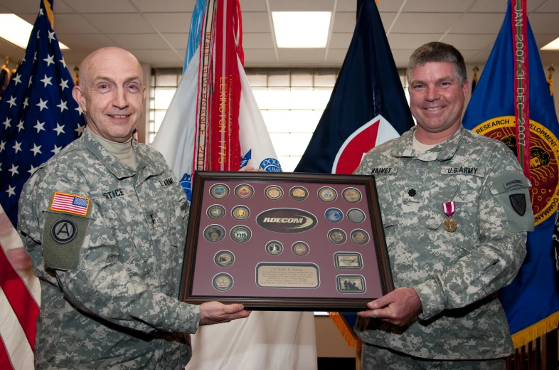 two men in fatigues hold a large plaque