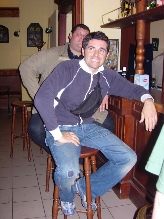 two men at a bar sitting on stools in the same area