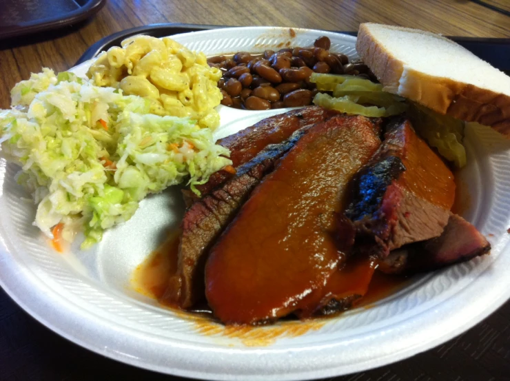 a large plate of meat and coleslaw on a paper plate