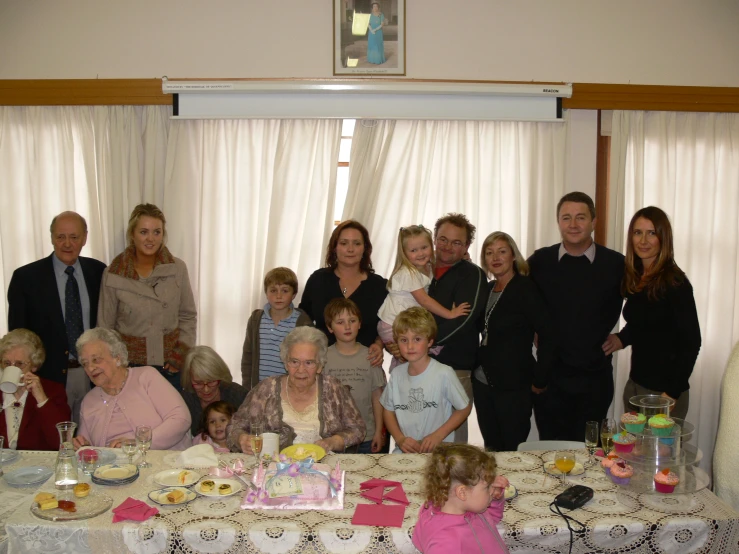 a group of people who are posing for a po in front of a cake