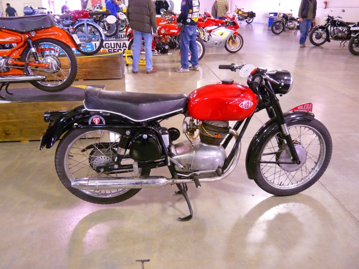 a red motorcycle sits on display with other people