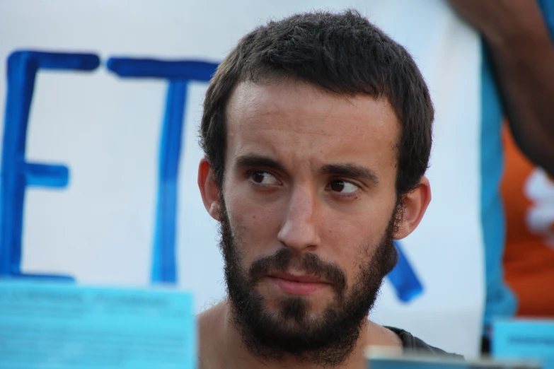 a man with dark hair and a beard staring into the camera