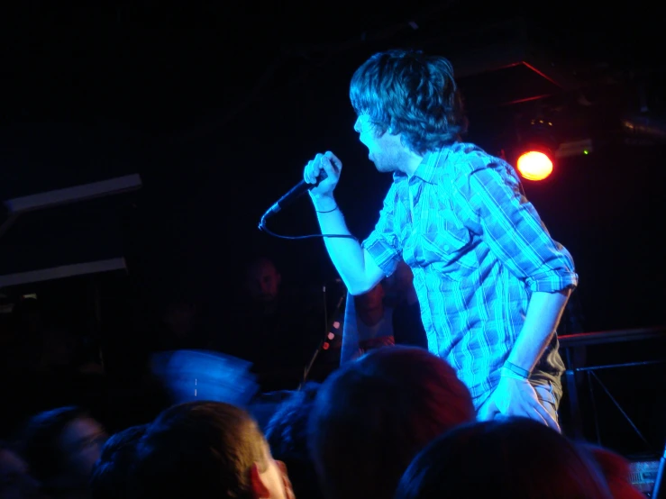 a young man standing on top of a stage while holding a microphone