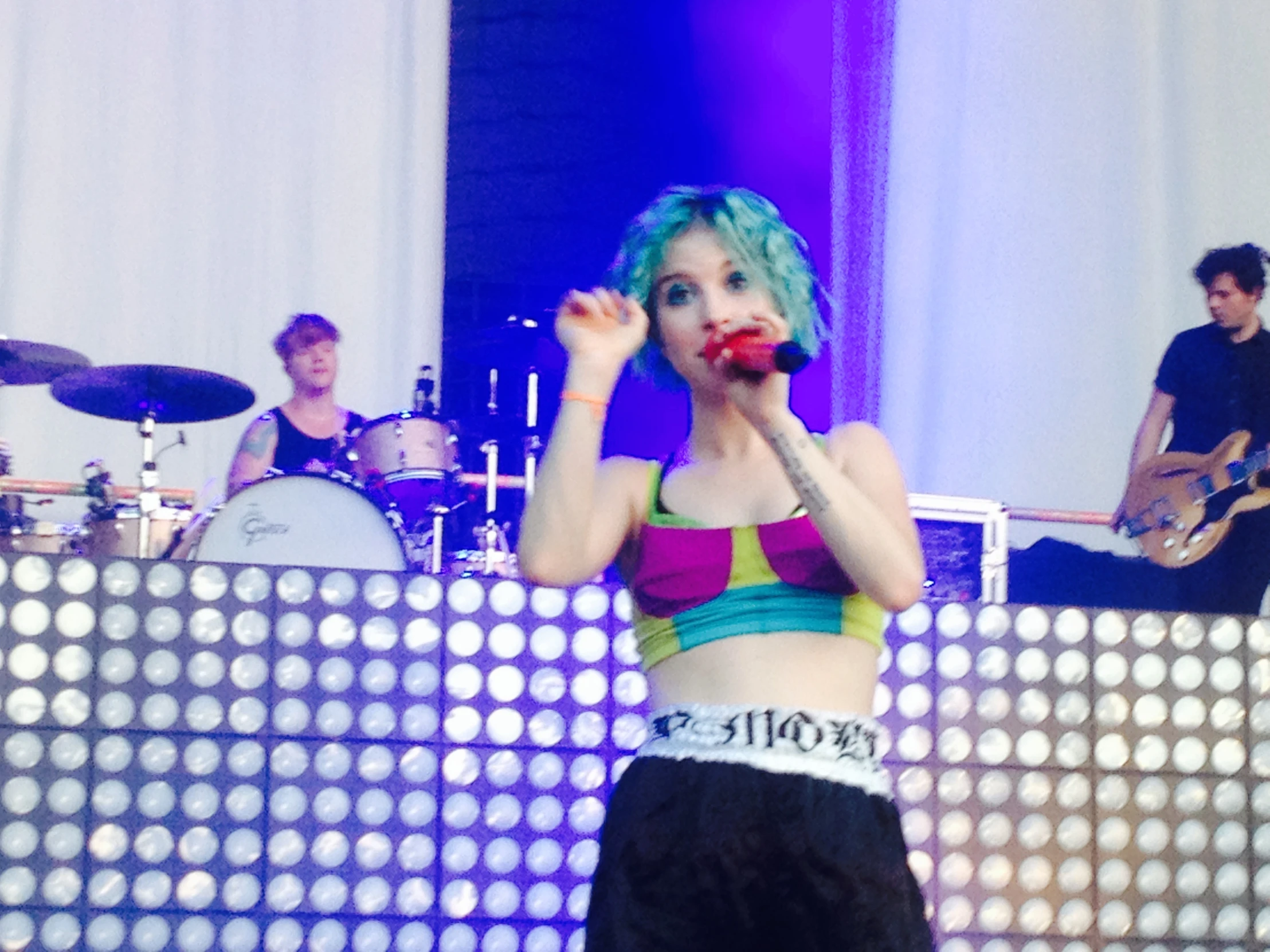 a person with colorful hair on stage holding up a microphone