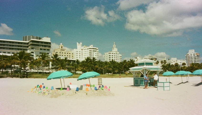 beach scene with blue umbrellas and building in background