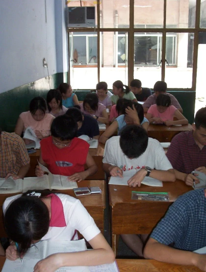 students taking test in a large classroom with lots of windows