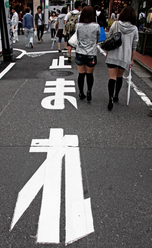 two women walking across a cross walk that has the word'love spelled in japanese