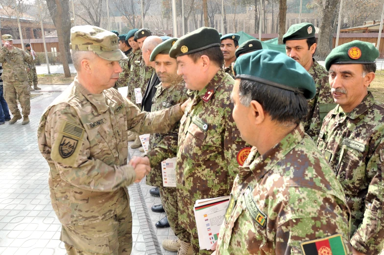 a group of men in uniform are shaking hands