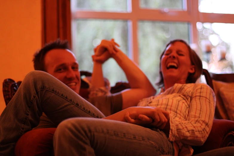 two people are sitting down on the couch and smiling