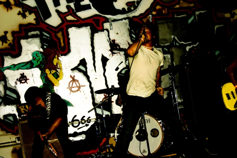 a group of men singing in front of graffiti